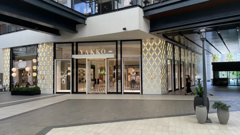 The front of a Vakko store in a mall in İzmir: a white and gold lattice wall, a glass door and the name VAKKO in capital letters over the entrance