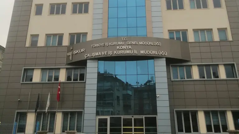 The front of a brick and glass office building with a curved sign that reads Türkiye İş Kurumu, İŞKUR and Konya Çalışma ve İş Kurumu İl Müdürlüğü, and a Turkish flag on a pole at the left