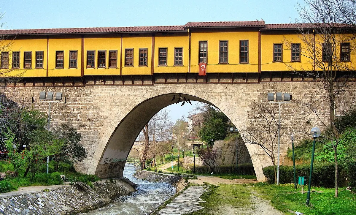 Irgandı Bridge in Bursa: a stone arch over the Gökdere stream carrying a yellow row of wooden shop houses along its deck