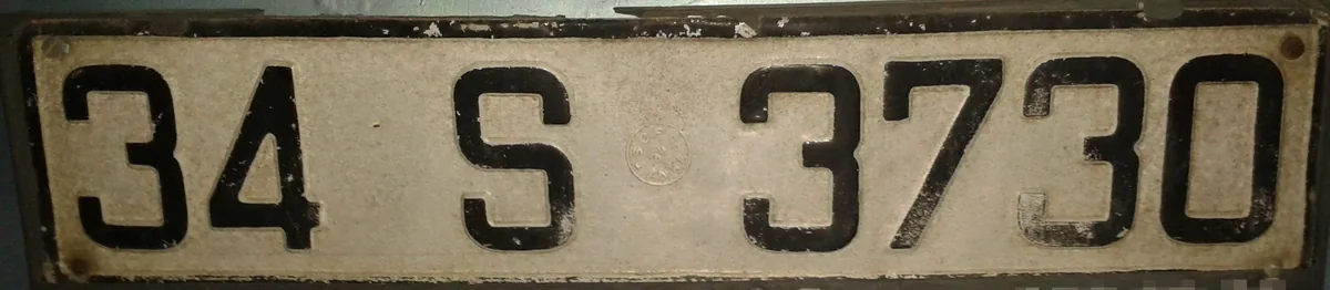 An old Turkish number plate: province code 34, the letter S and the digits 3730 in black on a pale plate