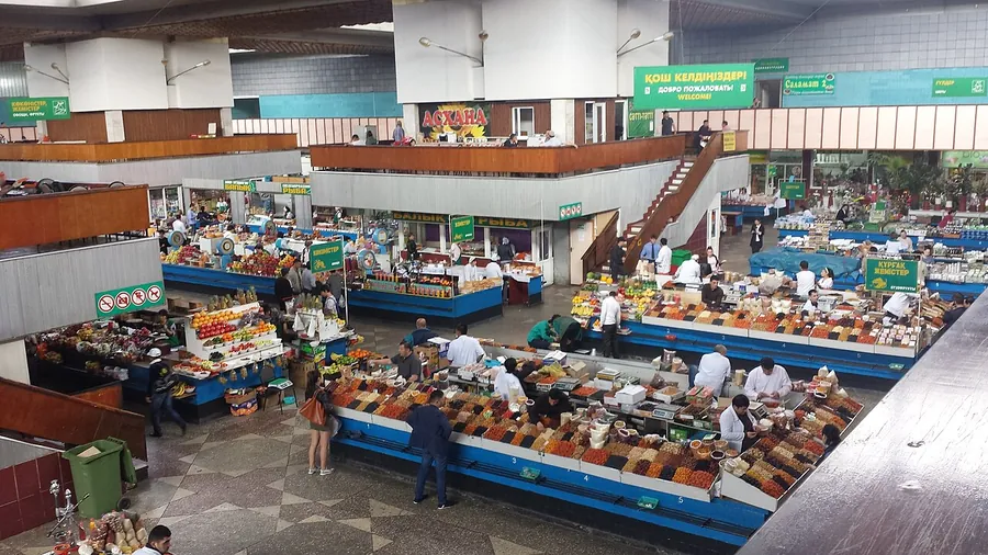 A large indoor market hall seen from above, with long counters of spices, dried fruit and other goods and people at the stalls