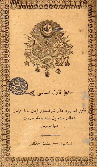 The printed title page of the Kanun-ı Esasi: a coat of arms with a crescent and a sultan&rsquo;s monogram above a heading in Ottoman Turkish in Arabic script, inside a decorated border, with the printer&rsquo;s name at the foot