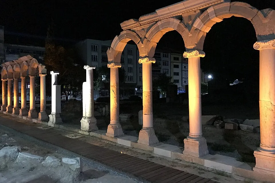推雅推喇遗址的石柱与一排拱门，夜间灯光照亮建筑，背后是漆黑的天空