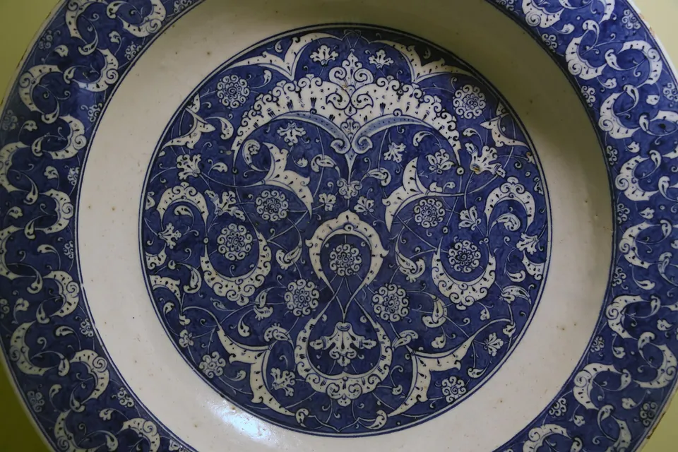 Dettaglio del centro dello stesso piatto: un medaglione blu di volute, foglie e piccole rosette su fondo bianco, con la bordura blu sopra e sotto