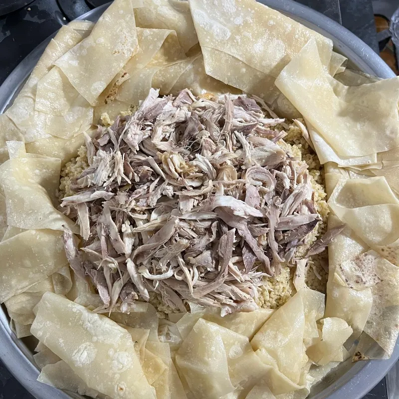 Un plateau rond o&ugrave; de la viande effiloch&eacute;e est dispos&eacute;e sur des c&eacute;r&eacute;ales et entour&eacute;e de feuilles de pain fin