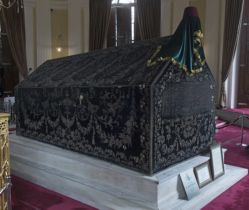 El sarc&oacute;fago de Mahmud II, una larga tela negra con bordados de plata y una tela verde con un fez en la cabecera, sobre una base de m&aacute;rmol