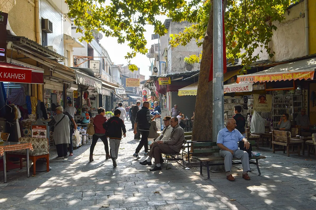 Σκιερό λιθόστρωτο στενό στο Κεμεραλτί με καφενεία, μαγαζιά κάτω από τέντες και άντρες καθισμένους σε παγκάκια κάτω από έναν πλάτανο