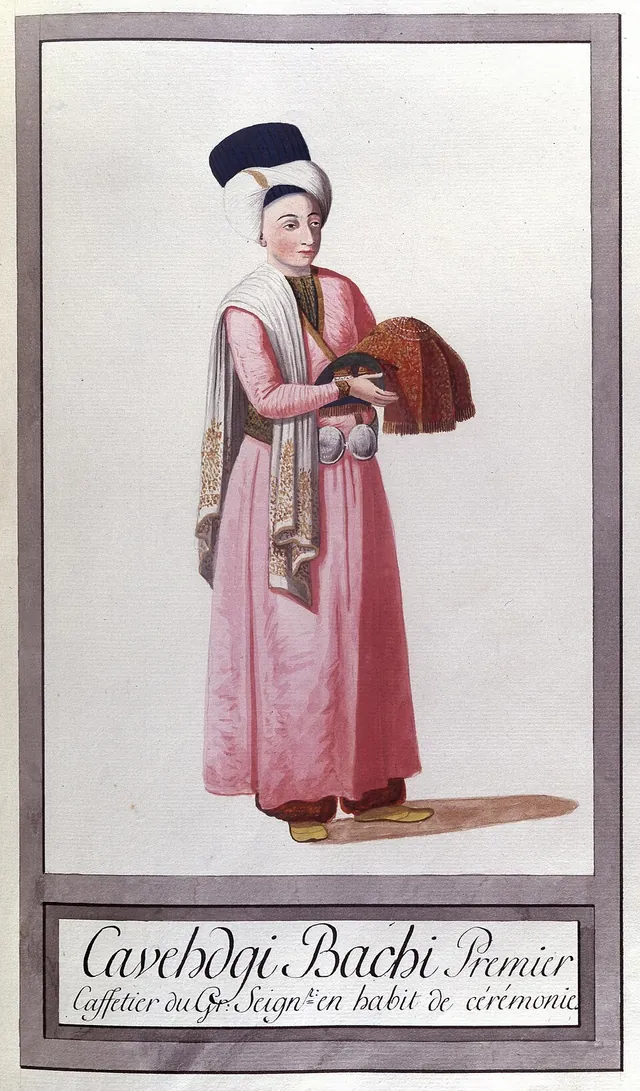 Uzun pembe kaftan ve yüksek, koyu renkli bir başlık giyen, elinde katlanmış kırmızı bir kumaş tutan ayakta bir figür; altında Fransızca bir açıklama var