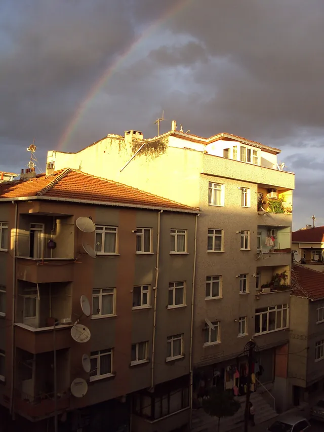 Apartment blocks on a street in Istanbul with a rainbow in the evening sky