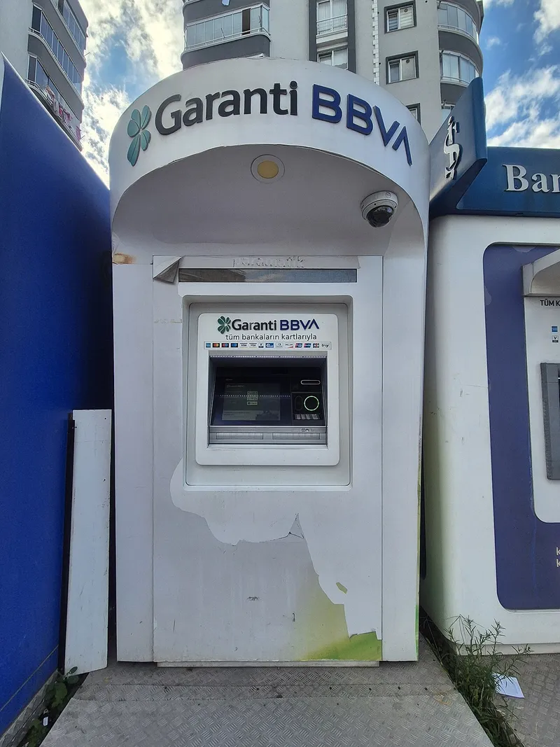 Kaldırım kenarında &uuml;st&uuml; kapalı bir kabin i&ccedil;indeki beyaz Garanti BBVA ATM'si