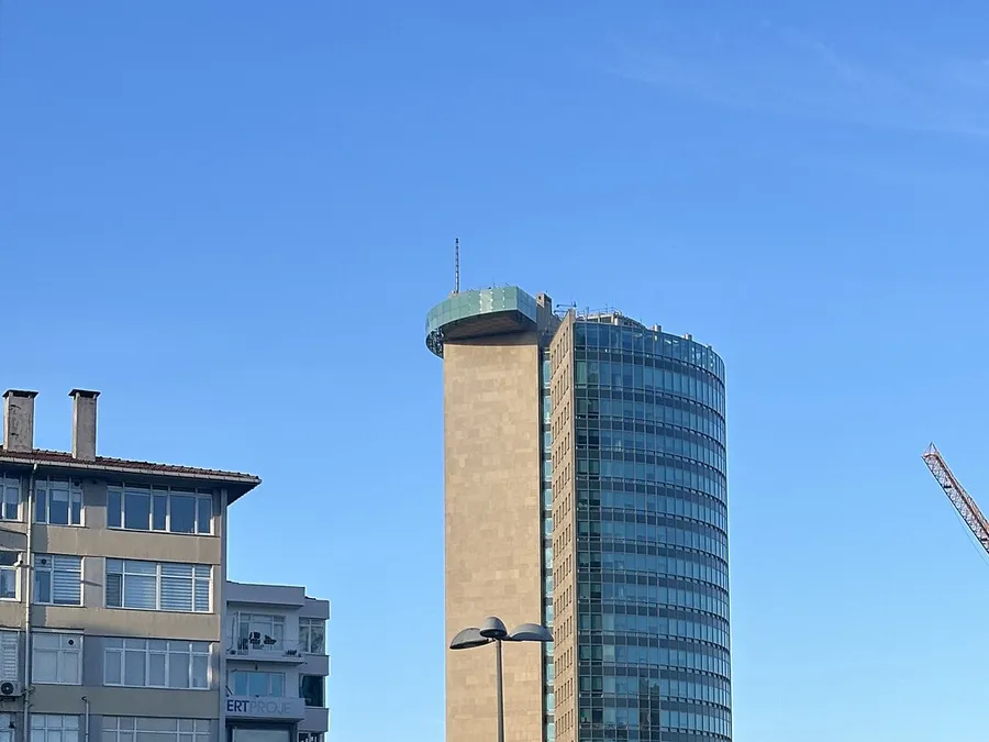 İstanbul'da bir yoldan, a&ccedil;ık mavi g&ouml;ky&uuml;z&uuml; altında g&ouml;r&uuml;len cam ve taş cepheli y&uuml;ksek bir ofis kulesi