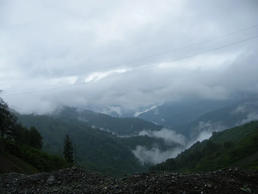 Un valle monta&ntilde;oso boscoso bajo nubes bajas, con niebla entre los pliegues de las laderas