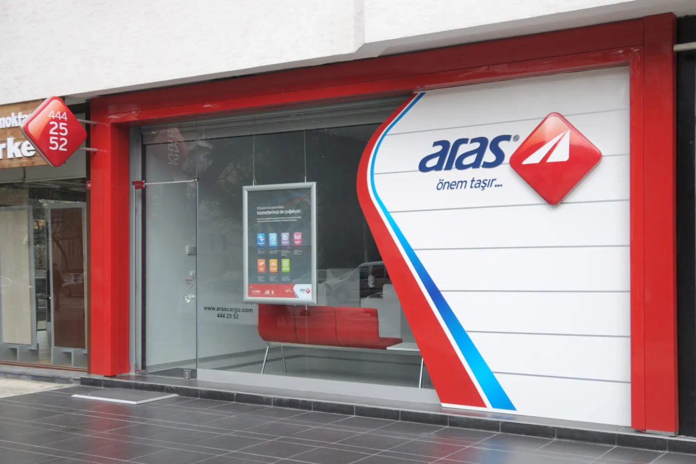 La façade vitrée d’une agence Aras Kargo avec l’enseigne Aras rouge et blanche.