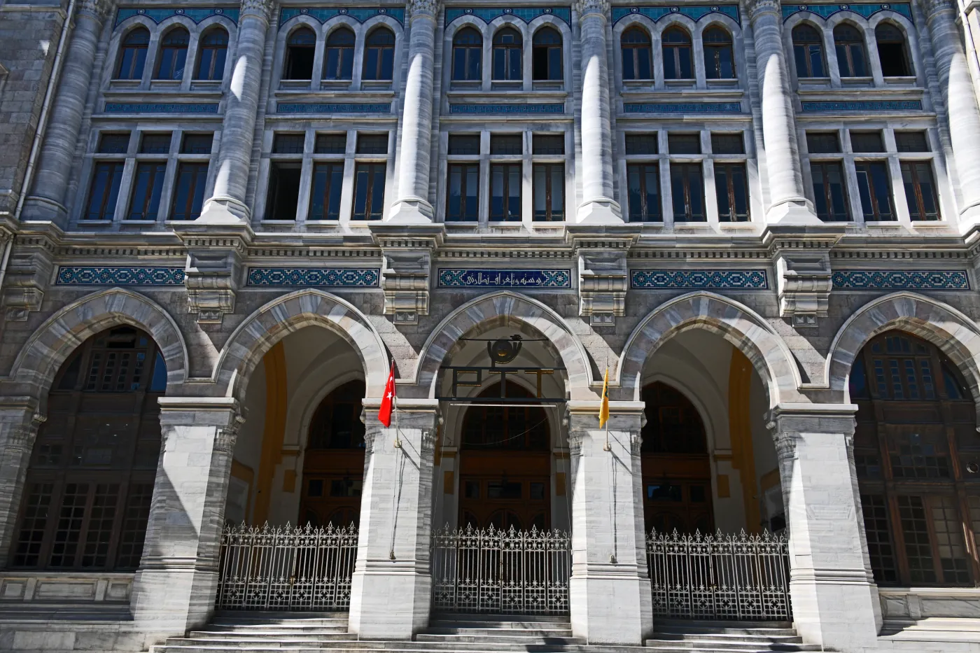 La façade en pierre d’un grand bureau de poste avec trois arches et une enseigne PTT au-dessus de celle du milieu.
