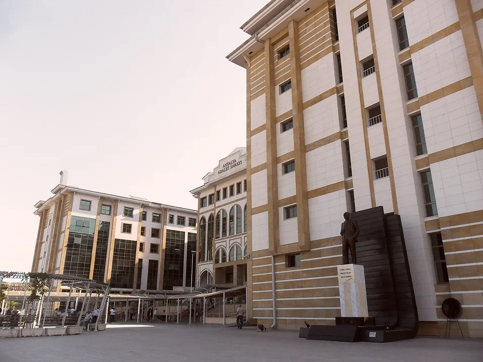 Un grand palais de justice de couleur crème avec une sculpture sombre sur l’esplanade devant le bâtiment
