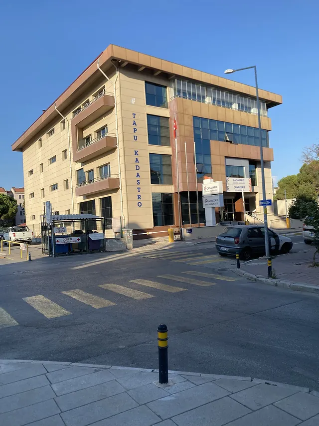 Un bâtiment beige du registre foncier avec une façade vitrée, vu depuis un angle de rue avec un passage piéton