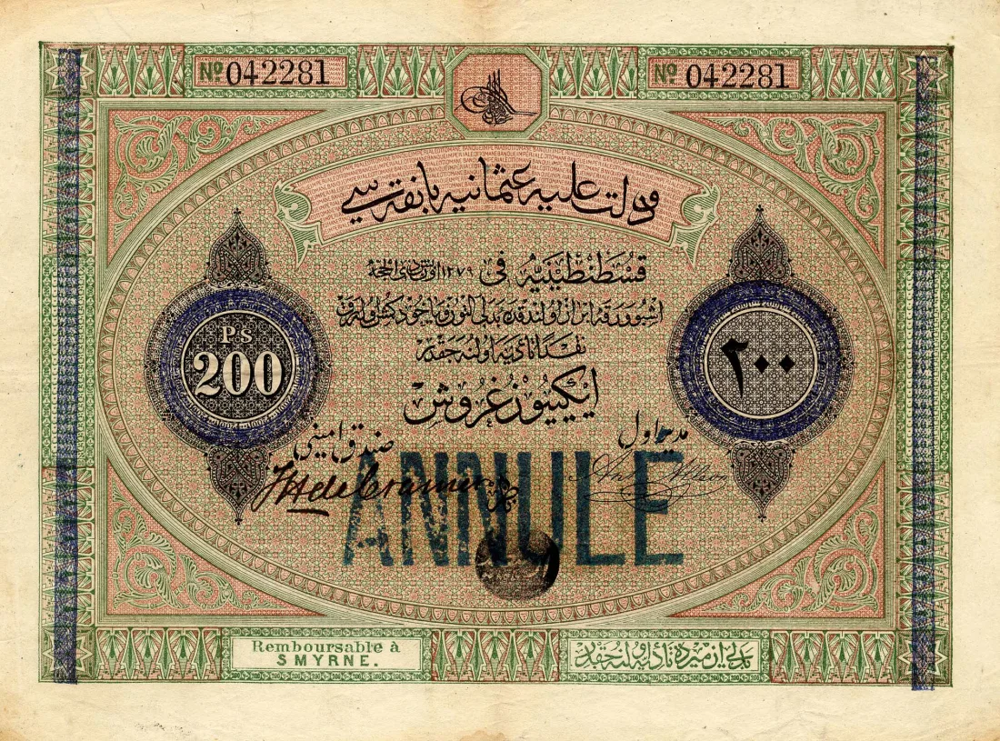 A cancelled 200-kuruş banknote of the Ottoman Bank: green, pink and blue ornamental print with the sultan's cipher at the top, Ottoman Turkish and French text, «Ps 200» in a round panel at the left, the number in Arabic figures at the right, the words «Remboursable à Smyrne» at the foot and a blue ANNULÉ stamp across the middle