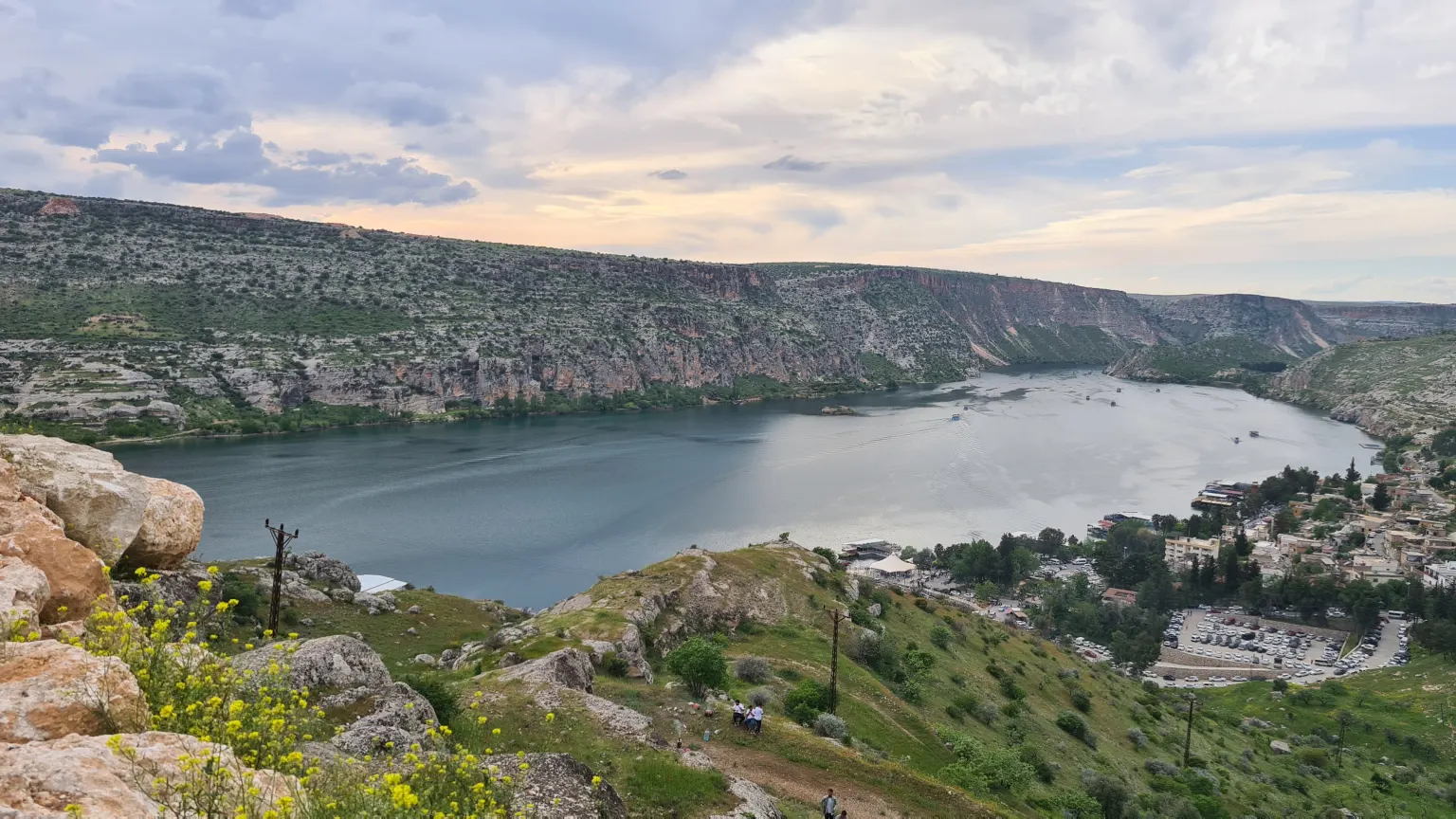 Un fleuve entre de hautes parois rocheuses, avec une petite ville sur la rive droite et quelques bateaux sur l’eau