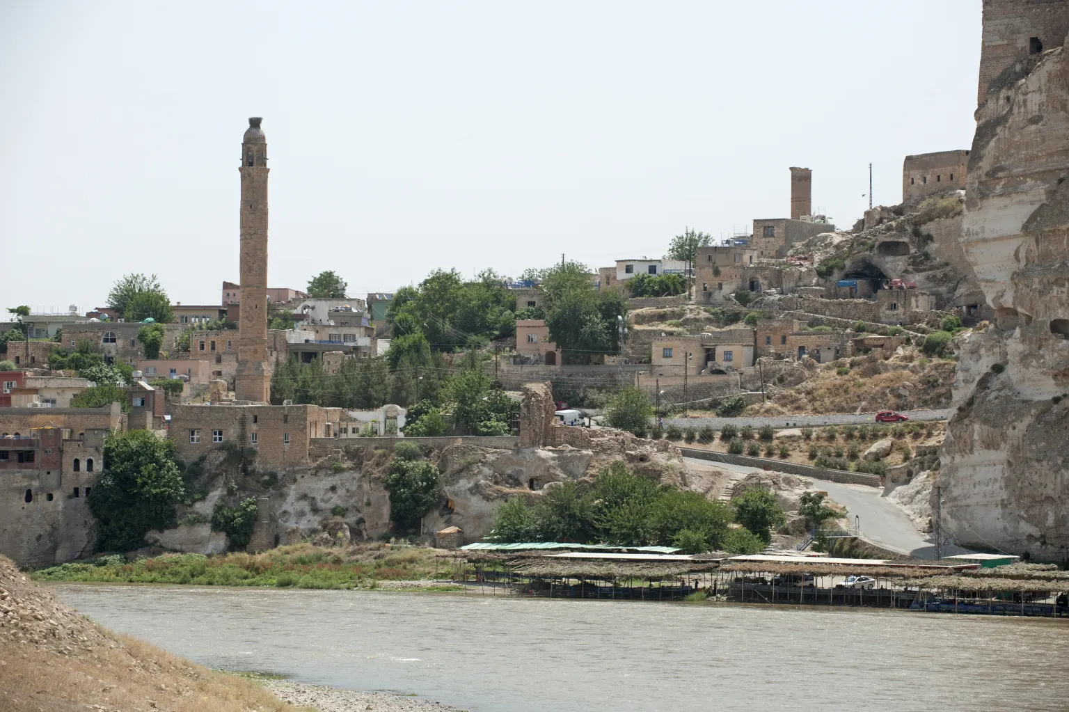 Des maisons en pierre et un minaret sur un rocher au-dessus d’un large fleuve